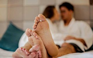 Two people in bed with their feet together.